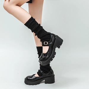 Detail view of black patent leather platform Mary Janes paired with knit leg warmers