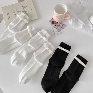 Detail view of chic white and black socks with elegant bow knots and pearl accents