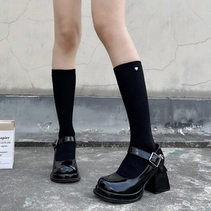 Detailed view of black Mary Jane shoes with silver heart-decorated knee-high socks