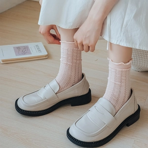 Detail of light pink hollow knit socks with ruffle edges paired with ivory platform loafers