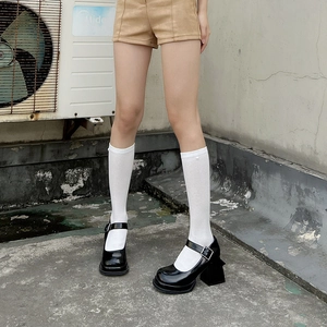 Detailed view of women's black platform Mary Jane shoes with white knee-high heart socks
