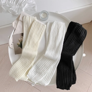 Knit leg warmers in white and black colors with a vertical ribbed texture in a tray