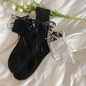 Detailed view of white and black mesh ballet socks with large satin bows and rib textures