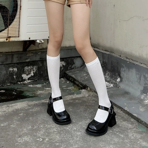 Detail of black patent leather Mary Jane shoes with thick heels and white calf socks
