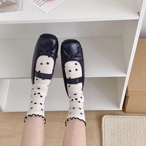 Close-up of black Mary Jane shoes with bow detail and white polka dot crew socks