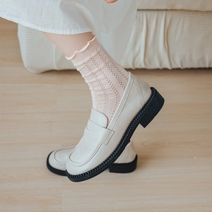 Chunky cream loafers with thick black soles paired with white lace ruffle socks