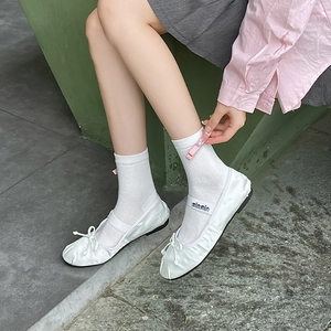 Detailed shot of white cotton socks featuring a delicate pink decorative 3D bow accent