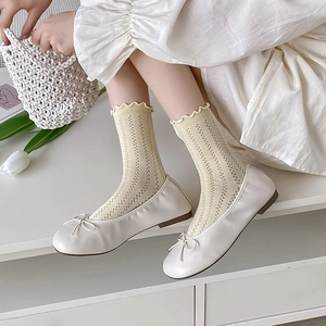 Detail of white ballet flats with bows and yellow mesh crew socks with ruffled edges