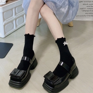 Black Mary Jane platform shoes with large bow and ruffled socks on model
