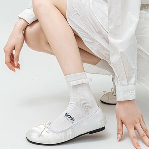 Detail of white ballet flats with ribbon bow pearl socks and branded elastic strap