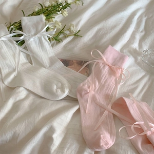 Detail of white and pink ballet-style socks with silk ribbons on soft fabric