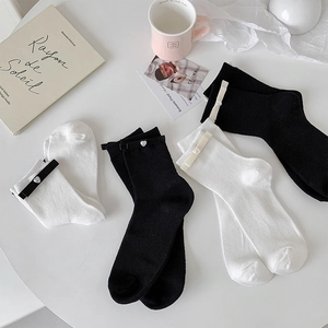 Detail of ribbon bows and heart pearl embellishments on white and black crew socks