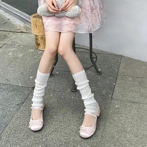 Detail of pink satin Mary Jane shoes with bows and white knitted slouch socks