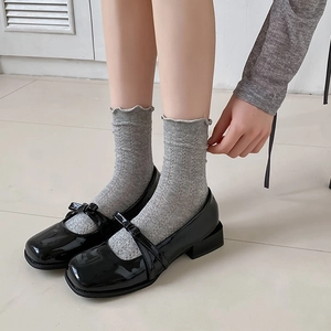 Close-up of black patent leather Mary Jane shoes with bow decoration and low block heels