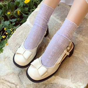 Beige Mary Jane shoes with lace mesh socks and bow details in a vintage garden setting