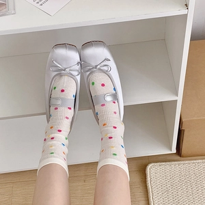 Detail view of silver satin Mary Jane flats with bow and colorful polka dot mesh socks