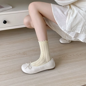 Detailed view of light yellow mesh knit socks featuring wavy scalloped edges and lace pattern