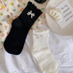 Detail of white and black JK calf socks featuring pearl bows and ruffled lace edges