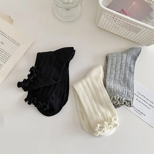 Flat lay of cotton crew socks with ribbed texture and ruffle cuffs in neutral tones