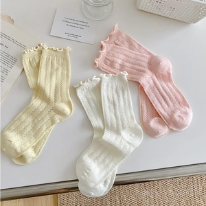 Detail of ruffle edges and hollow knit texture on three pastel mid-calf socks