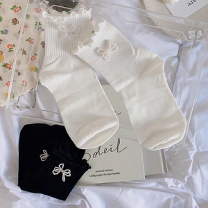Detail of JK style mid-calf socks with pearl bowknot and frilly lace trim in white and black