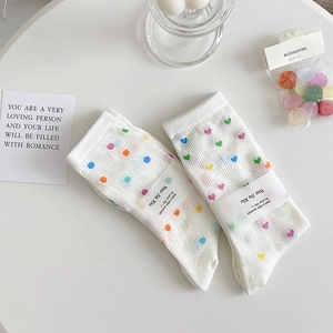 Detail of white mesh crew socks featuring colorful polka dots and heart patterns