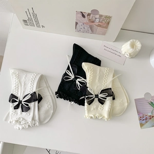 Detail of Lolita style calf socks with layered bows, lace ruffles and textured knit fabric
