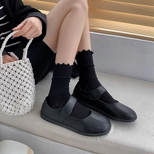 Classic black Mary Jane shoes with mesh socks shown on a minimal staircase
