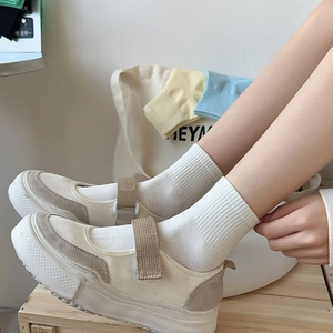 Close-up of off-white Mary Jane sneakers with thick soles and velcro straps on a model