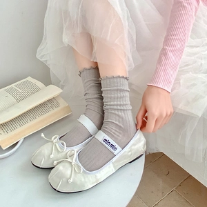 Detail of white Mary Jane shoes with bow decoration and grey striped mesh socks
