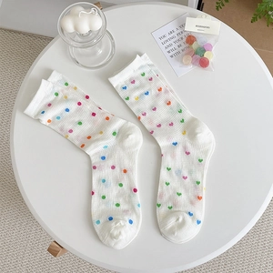 Detail of white mesh mid-calf socks with colorful polka dots and heart patterns