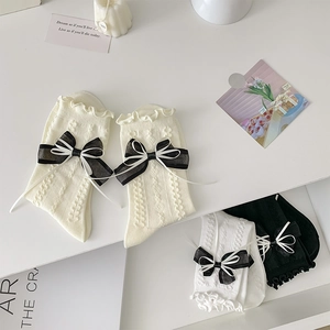 Detailed macro view of white Lolita socks featuring ruffled edges and ribbon bows