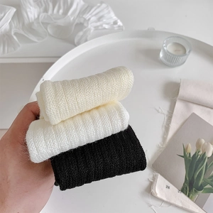 Close-up of ribbed knit leg warmers in white and black with a soft textured finish