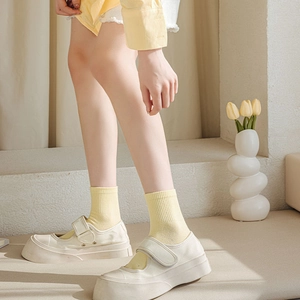 Detail of off-white platform canvas shoes with yellow socks and velcro strap