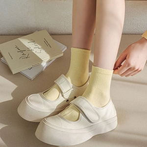 Close-up of beige Mary Jane platform shoes paired with yellow knitted crew socks