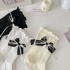 Detail showing ruffled lace edges and double bow accents on high cotton knit socks
