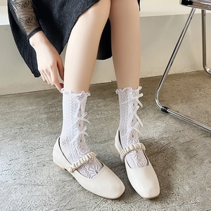Detailansicht weißer hohler Spitzensocken mit Seidenschleifen und Mary Jane Schuhen