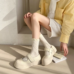 Detail of white lace mid-calf socks with textured knit and cream platform Mary Jane shoes