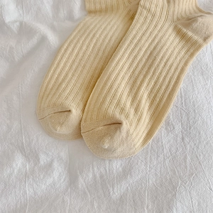 Close-up of light yellow ribbed knit cotton socks on white fabric background