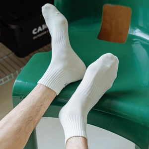 Close-up of white cotton crew socks featuring blue letter embroidery and ribbed cuffs