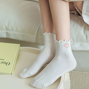 Détail de chaussettes blanches à volants avec broderie cœur rose et texte Nice sur le côté