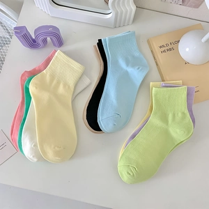 Detail of candy-colored ribbed cotton socks in various macaron tones on a white desk