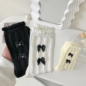Détail de chaussettes en tricot JK avec volants, accents de perles et nœuds en soie
