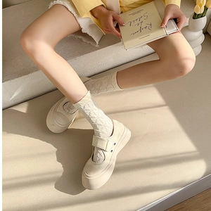 Detail of white lace jacquard socks paired with beige platform Mary Jane canvas shoes