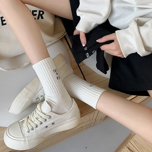 Detail of ribbed cotton mid-calf socks featuring letter embroidery and striped knit texture