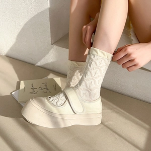 Detail of beige platform Mary Janes with lace socks and velcro strap on stairs