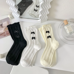 Détail de chaussettes JK à volants avec torsades et nœuds noirs perlés