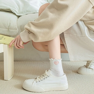 Gros plan sur des chaussettes blanches à volants avec broderie coeur rose et Nice