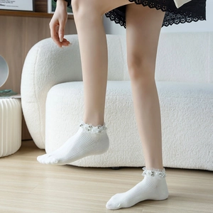 Detailed view of white cotton socks featuring delicate lace edges and pearl bead accents