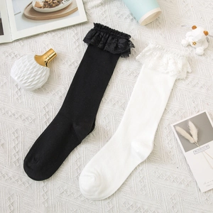 Flat lay of lace trim knee-high socks in black and white with elegant lifestyle props